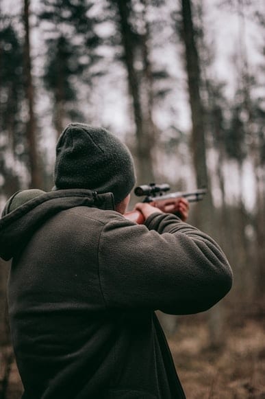 A man holding a rifle in the woods.