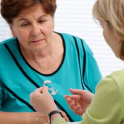 Audiologist showing a patient how to use hearing aids.