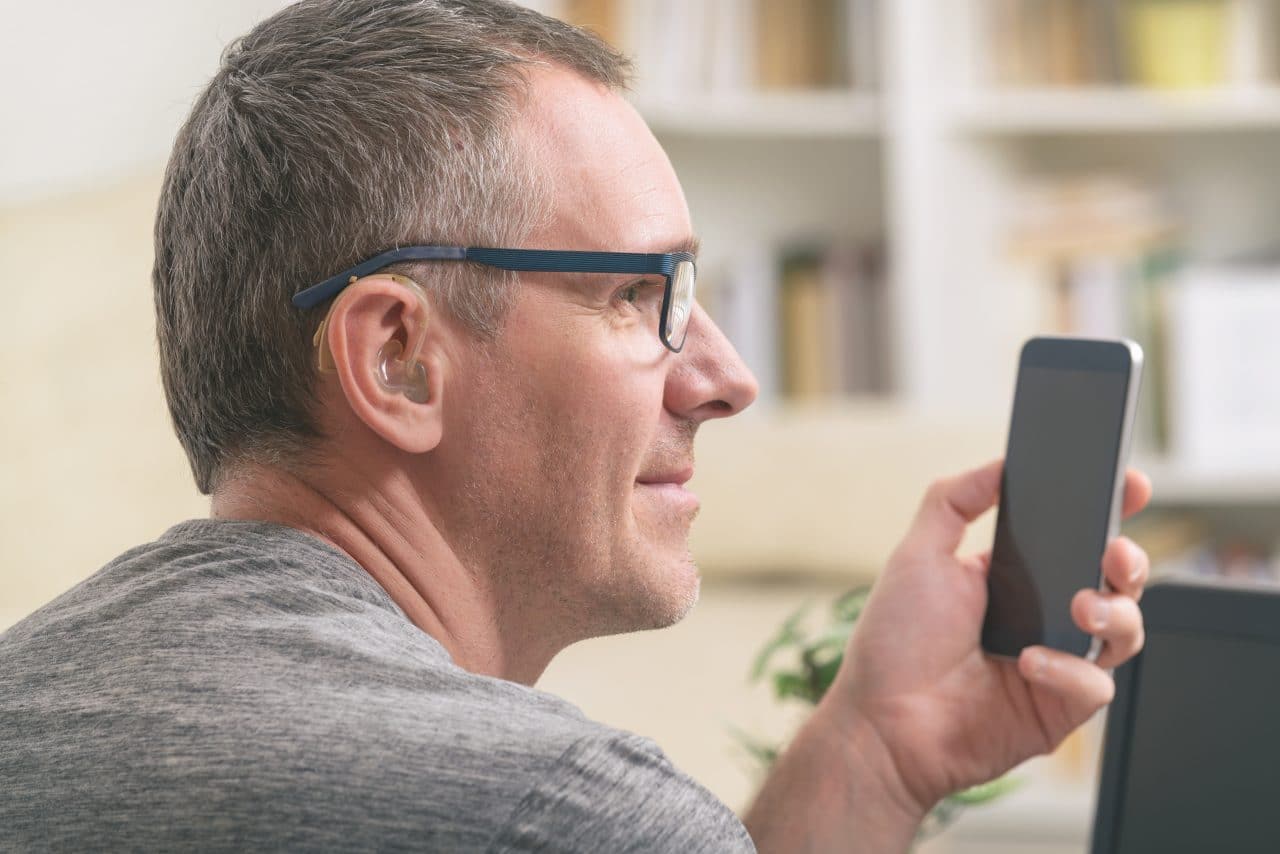 Man with hearing aid on smartphone