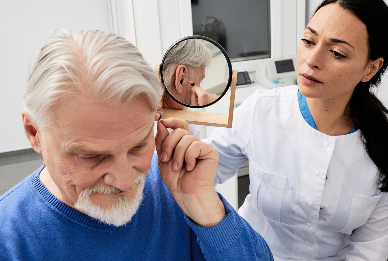 Senior man putting in an ITC hearing aid